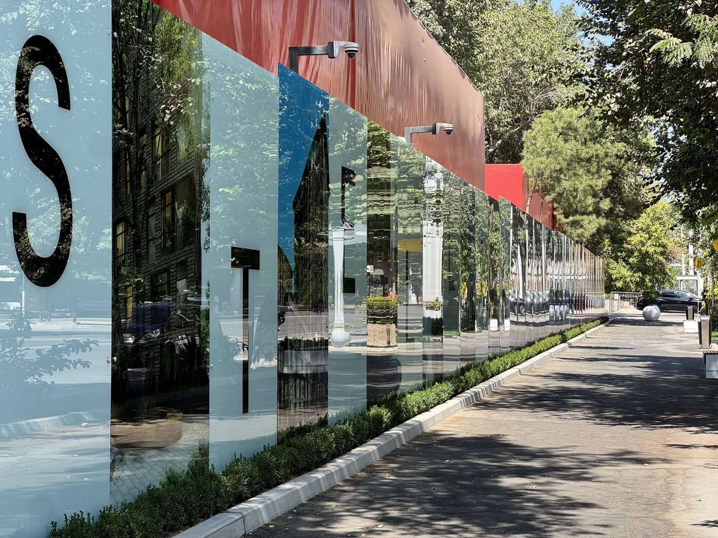 Mirror glass hoarding panels reflecting the street and trees